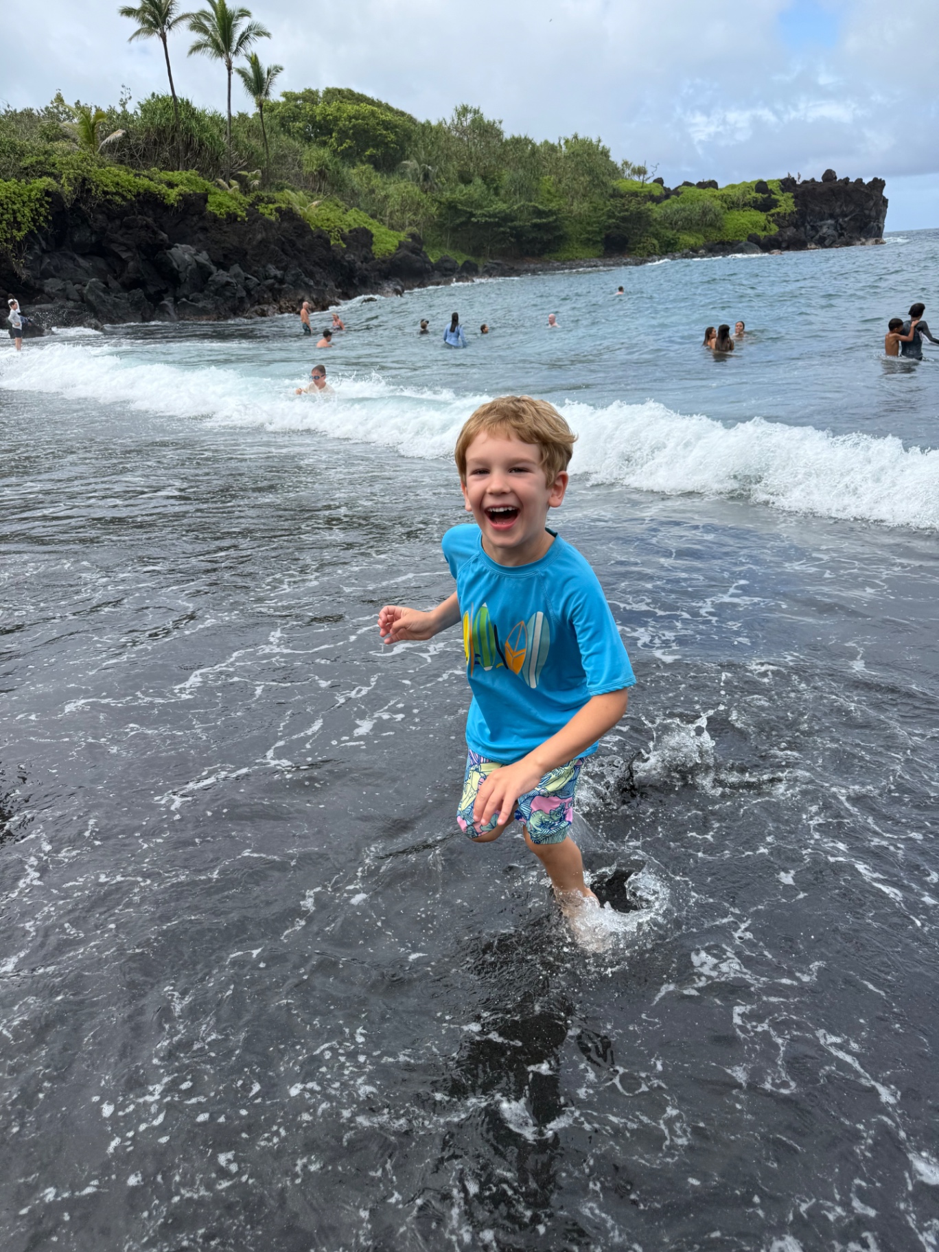 A boy playing in the surf at a black sand beach