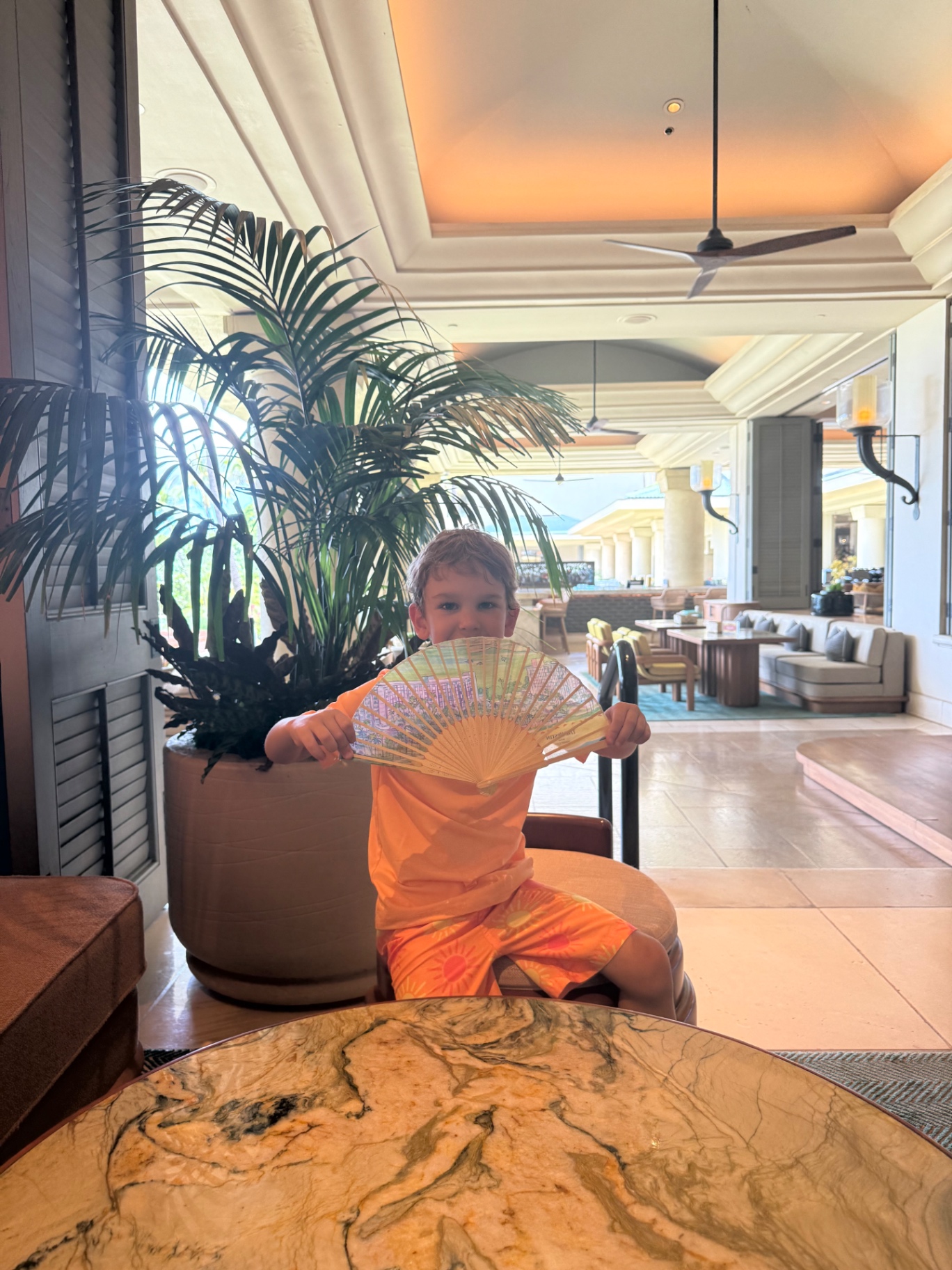 A child with a souvenir fan in a resort lobby