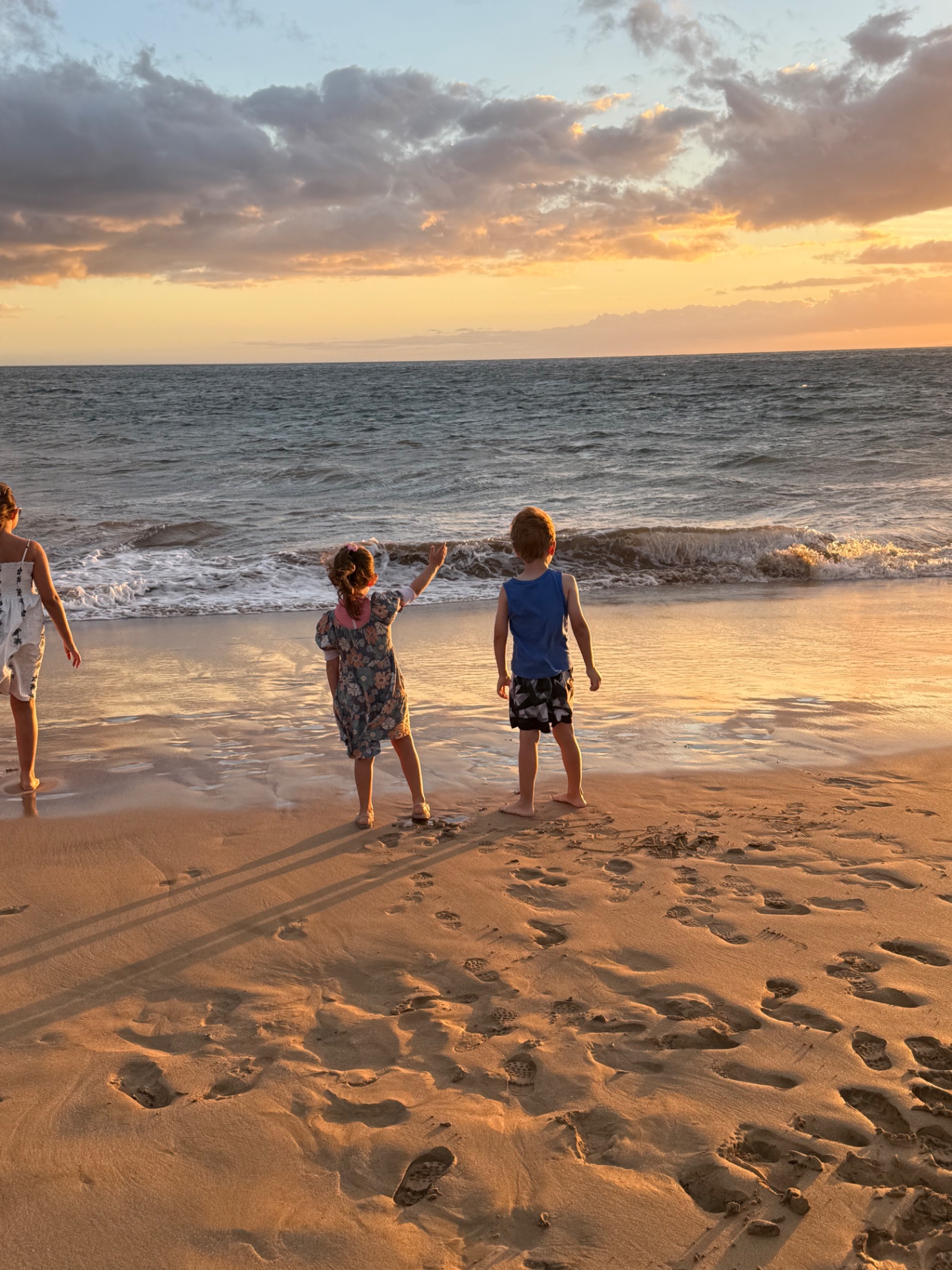 Kids playing in the waves at sunset on a Maui beach